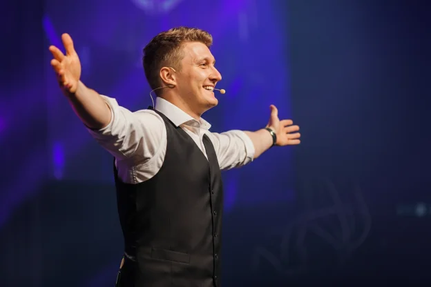 Magiske Daniel som konferansier for bedrifter i Kristiansand strekker hendene mot publikum